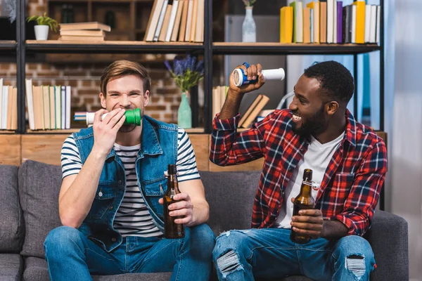 Счастливые молодые многонациональные друзья пьют пиво и смотрят телевизор — стоковое фото