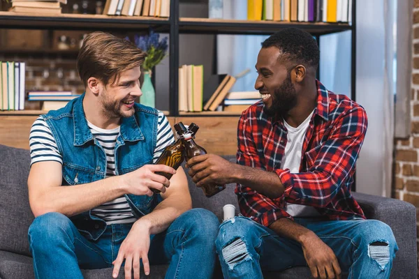 Happy young multiethnic men clinking bottles of beer — Stock Photo