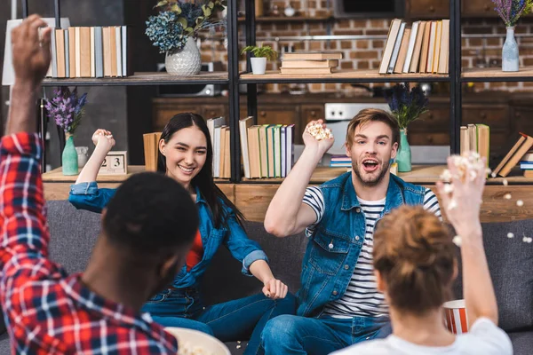 Happy young multiethnic friends throwing popcorn and having fun together — Stock Photo