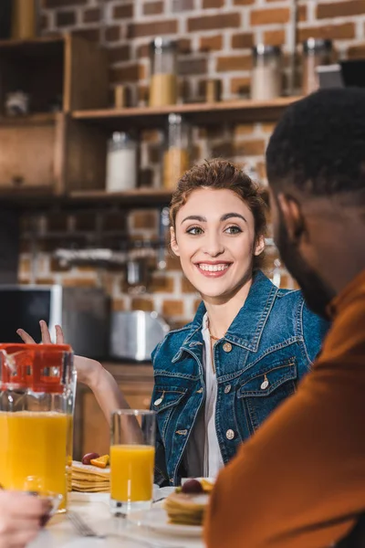Schnappschuss eines lächelnden jungen multiethnischen Paares beim gemeinsamen Frühstück zu Hause — Stockfoto