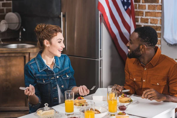 Feliz jovem casal multiétnico tomando café da manhã juntos em casa — Fotografia de Stock