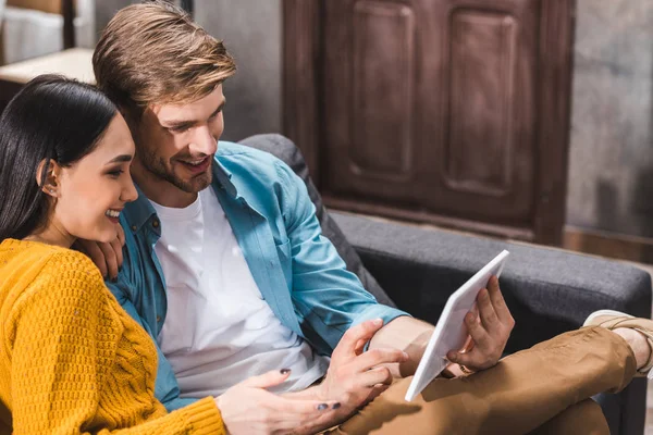 Glückliches junges multiethnisches Paar mit digitalem Tablet zu Hause — Stockfoto