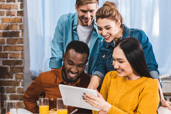 Felices jóvenes amigos multiétnicos utilizando tableta digital juntos - foto de stock