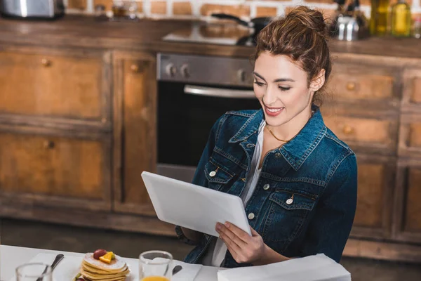 Hermosa mujer joven sonriente usando tableta digital en casa - foto de stock