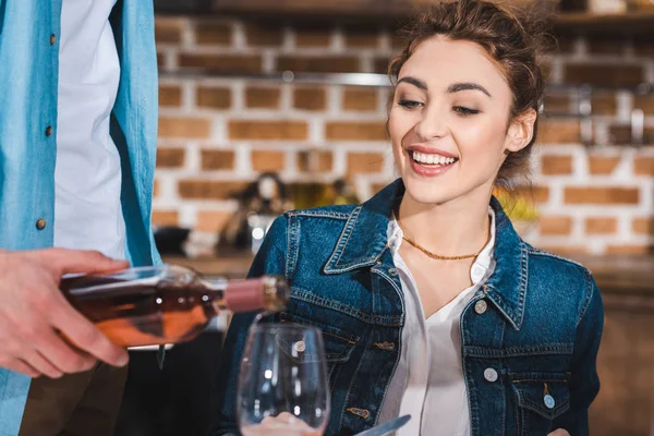 Cropped shot of man pouring wine to smiling girlfriend at home — Stock Photo