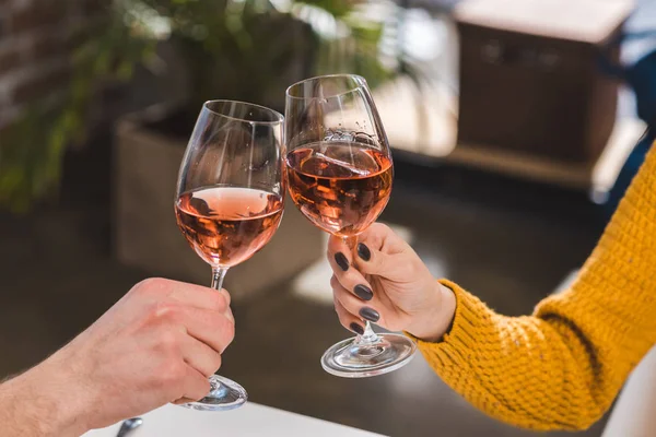 Close-up partial view of couple clinking wine glasses at home — Stock Photo