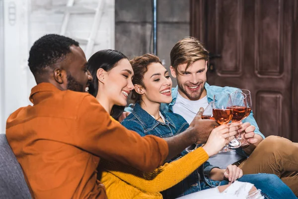 Happy young multiethnic friends clinking wine glasses — Stock Photo