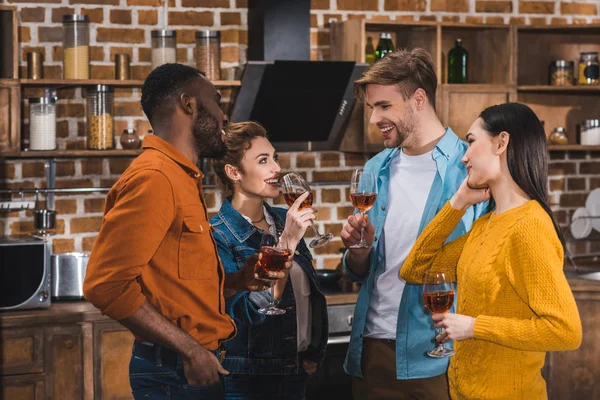 Felici giovani amici multietnici che bevono vino e si sorridono a casa — Foto stock