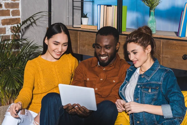 Felizes jovens amigos multiétnicos usando tablet digital juntos em casa — Fotografia de Stock