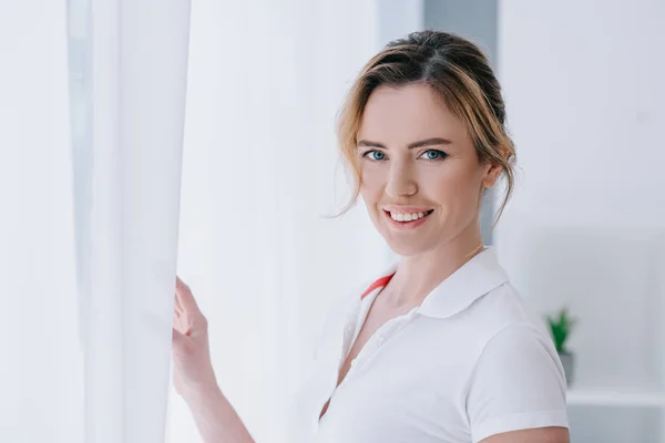 Atractiva mujer adulta de pie cerca de la ventana - foto de stock