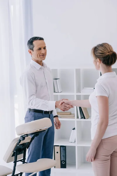 Businessman shaking hand of masseuse at office — Stock Photo