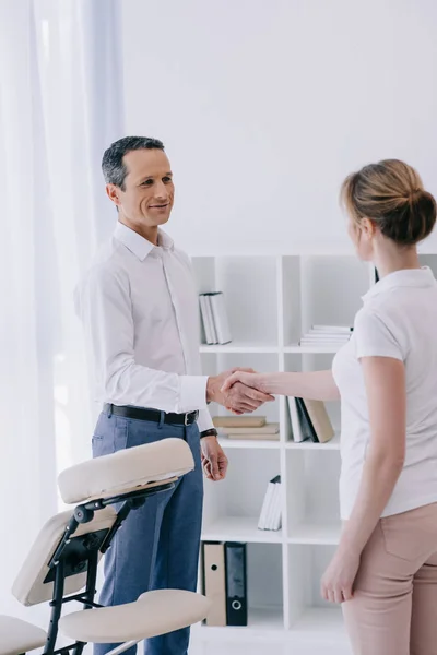 Homme d'affaires serrant la main de masseuse au bureau — Photo de stock