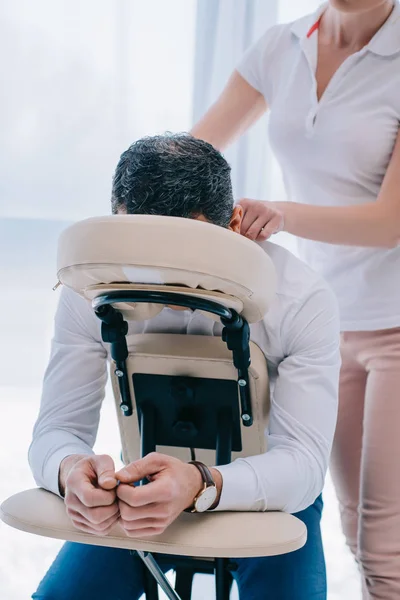 Massagista fazendo massagem nos ombros no assento no escritório — Fotografia de Stock