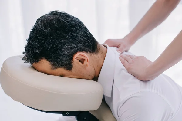 Primer plano de masajista haciendo masaje de espalda sentado para hombre de negocios - foto de stock