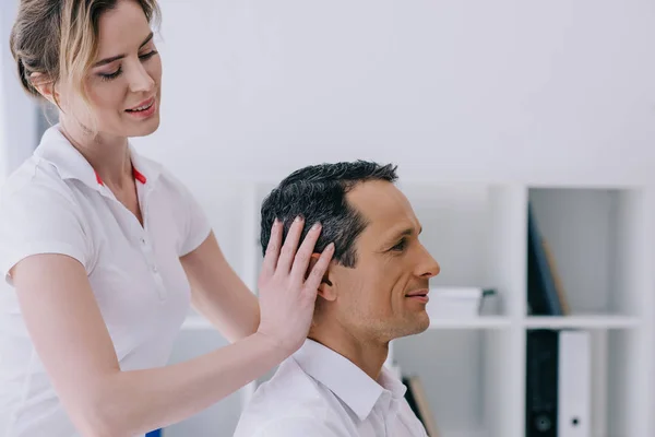 Side view of masseuse doing head massage for handsome mature businessman — Stock Photo