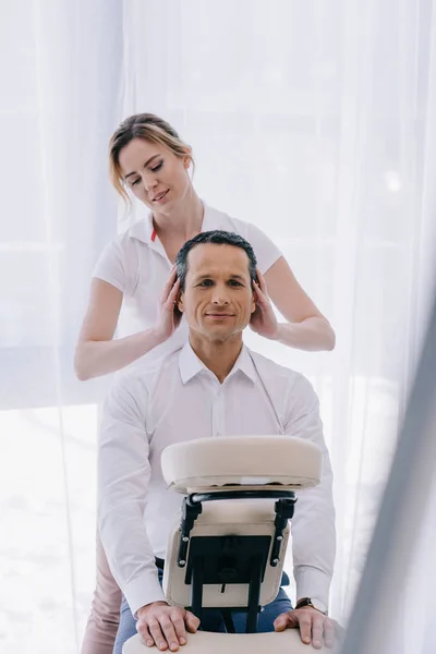Massagista fazendo massagem na cabeça para belo homem de negócios maduro — Fotografia de Stock