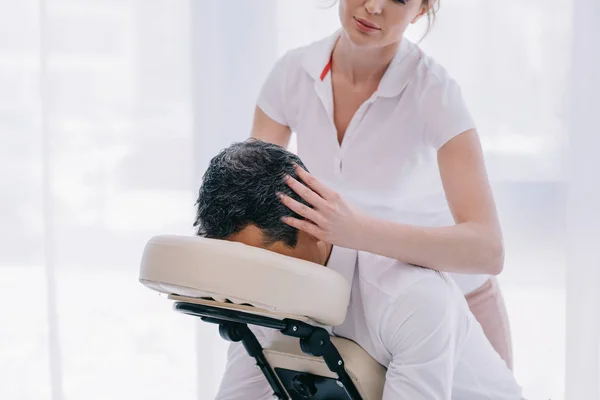 Atractiva masajista haciendo masaje en la cabeza para hombre de negocios - foto de stock