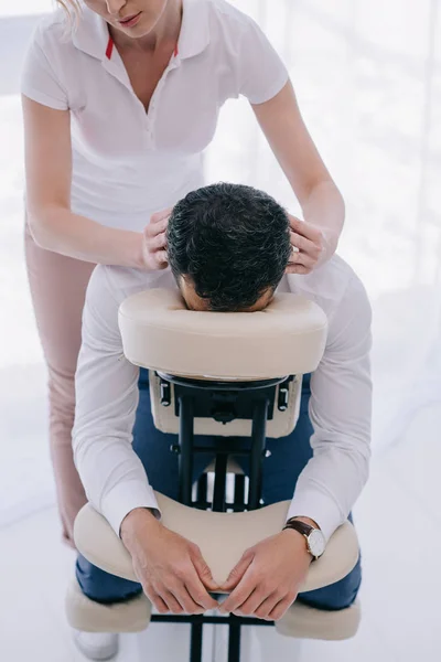 Visão de alto ângulo de massagista fazendo massagem na cabeça para homem de negócios — Fotografia de Stock