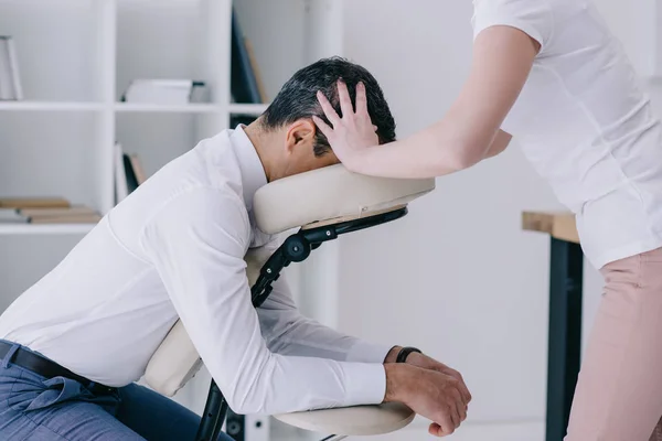 Massagista fazendo massagem na cabeça sentada para homem de negócios — Fotografia de Stock