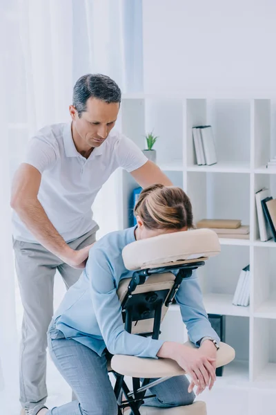 Schöner reifer Masseur tut sitzende Massage für Geschäftsfrau — Stockfoto