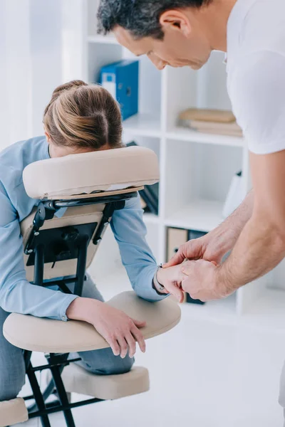 Masajista haciendo manos masaje para mujer de negocios - foto de stock