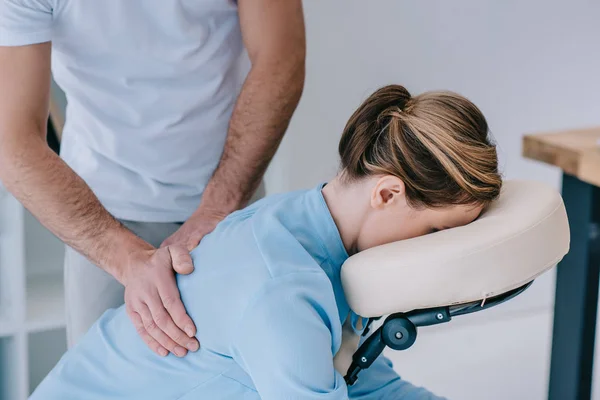 Primer plano de masajista masajeando espalda de cliente femenino - foto de stock