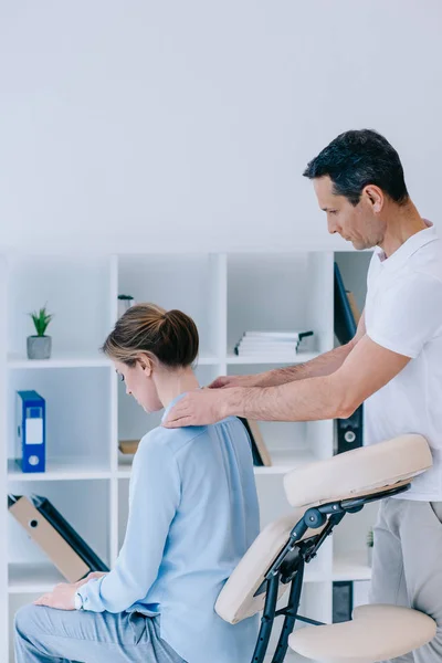 Masseur massaging shoulders of female client — Stock Photo