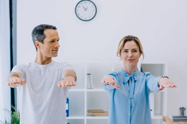 Feliz hermosa mujer de negocios haciendo ejercicio con entrenador en la oficina - foto de stock