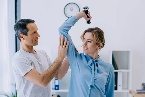 Businesswoman and her mature personal trainer doing exercise with dumbbell at office — Stock Photo