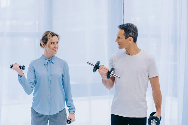Businesswoman and her personal trainer working out with dumbbells at office — Stock Photo