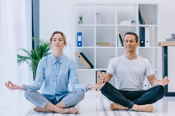 Geschäftsfrau meditiert mit ihrem Trainer in Lotus-Pose im Büro — Stockfoto