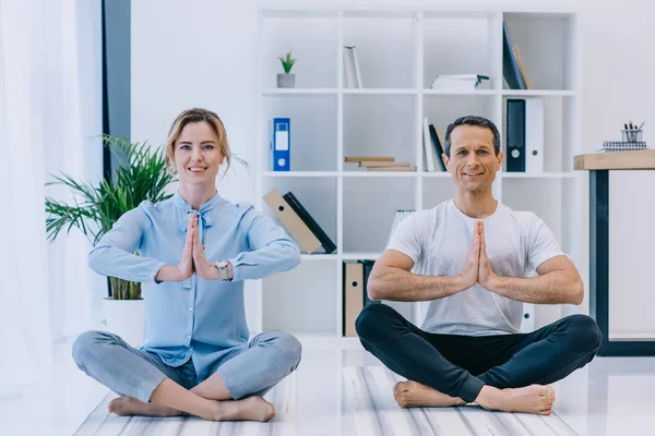 Geschäftsfrau mit ihrem Trainer, der im Büro in Lotus-Pose Yoga praktiziert — Stockfoto