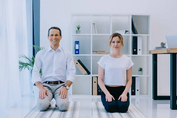 Uomo d'affari con il suo allenatore meditando su stuoie di yoga in ufficio — Foto stock