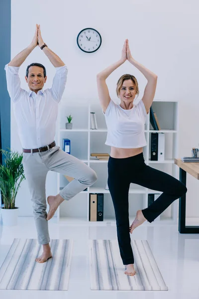 Businessman with his trainer practicing yoga in tree pose at office — Stock Photo