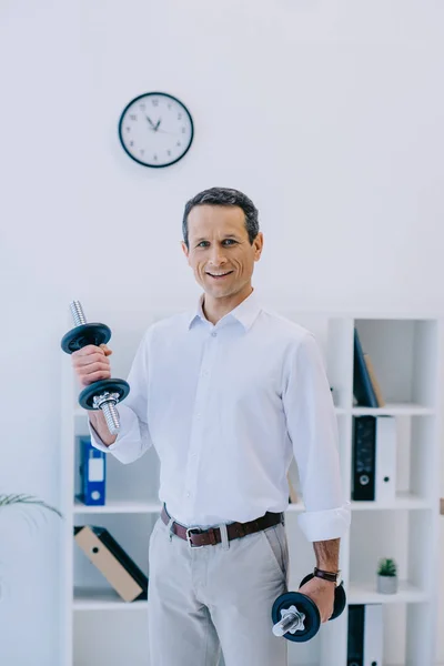 Heureux homme d'affaires mature travailler avec haltère au bureau — Photo de stock