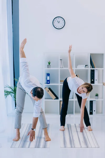 Homme d'affaires avec son entraîneur pratiquant le yoga en pose triangle au bureau — Photo de stock