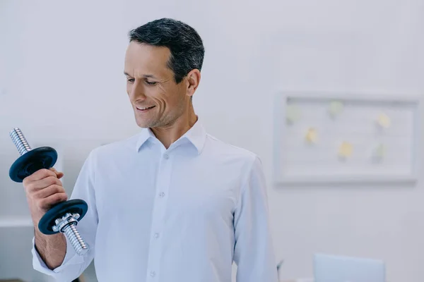 Fit mature businessman workign out with dumbbell at office — Stock Photo