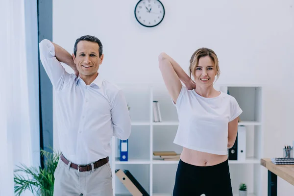 Happy mature businessman stretching before workout with personal trainer — Stock Photo