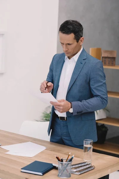 Konzentrierter erwachsener Geschäftsmann liest Geschäftszeitung im Büro — Stockfoto