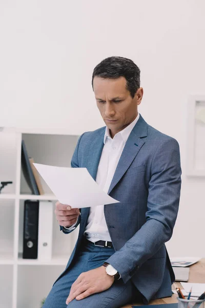 Handsome businessman reading business paper at office — Stock Photo