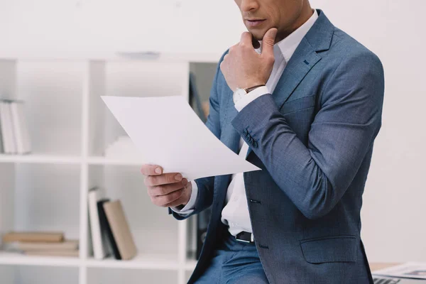 Plan recadré d'homme d'affaires réfléchi lecture papier d'affaires au bureau — Photo de stock