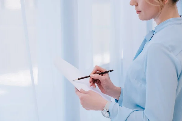 Recortado tiro de mujer de negocios con lápiz lectura documento - foto de stock