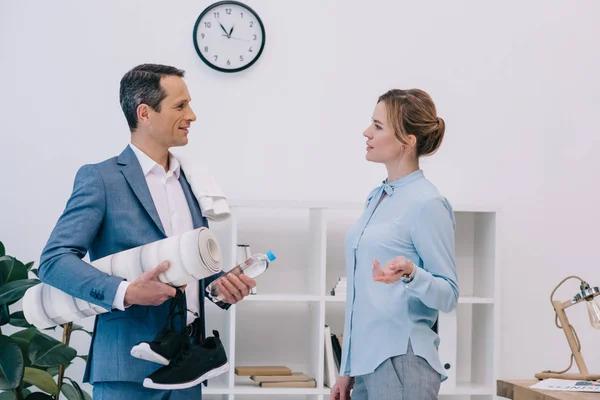 Homme d'affaires mature avec équipement de fitness bavarder avec un collègue avant la formation au bureau — Photo de stock