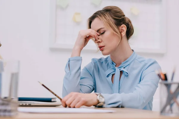 Exhausted adult businesswoman sitting at workplace in office — Stock Photo