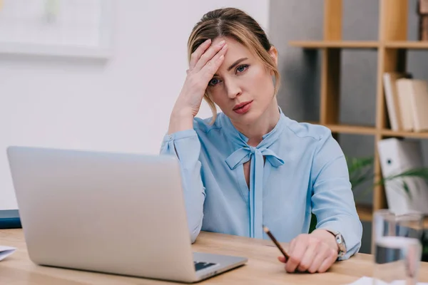 Femme d'affaires surmenée avec migraine assis sur le lieu de travail au bureau — Photo de stock