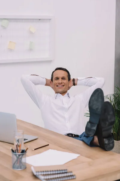 Schöner glücklicher Geschäftsmann entspannt sich am Arbeitsplatz im Büro — Stockfoto