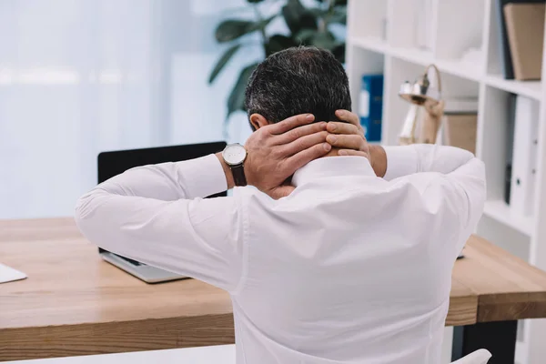 Vue arrière de l'homme d'affaires avec douleur au cou au travail au bureau — Photo de stock