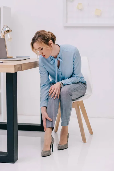 Femme d'affaires avec douleur à la cheville sur le lieu de travail — Photo de stock