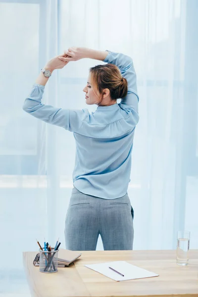 Vue arrière d'une femme d'affaires attrayante faisant de la gymnastique matinale au bureau — Photo de stock