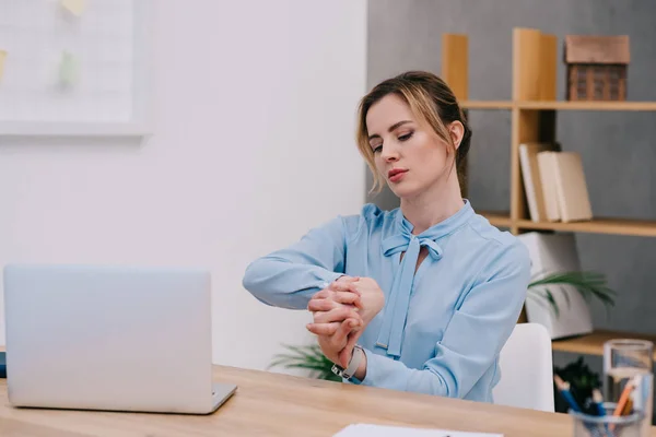 Atractiva mujer de negocios estirando las manos en el lugar de trabajo en la oficina - foto de stock